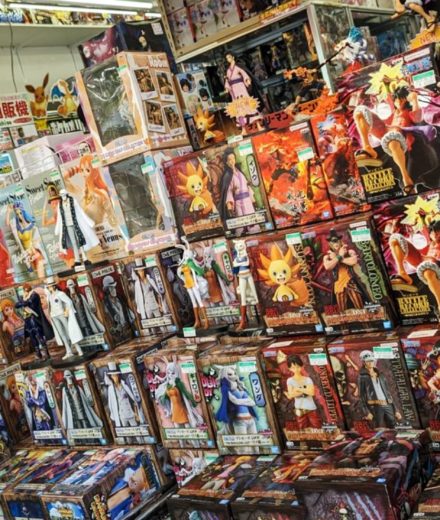 Étalage de figurines d’anime en magasin spécialisé, présentant différentes gammes de figures de collection sous vitrine.