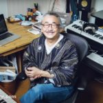 Choisir sa première figurine, c’est déjà choisir la collection qu’on veut construire Nobuo Uematsu sourit au milieu de son matériel de création, entouré d’un ordinateur, d’un clavier et de son espace de travail.