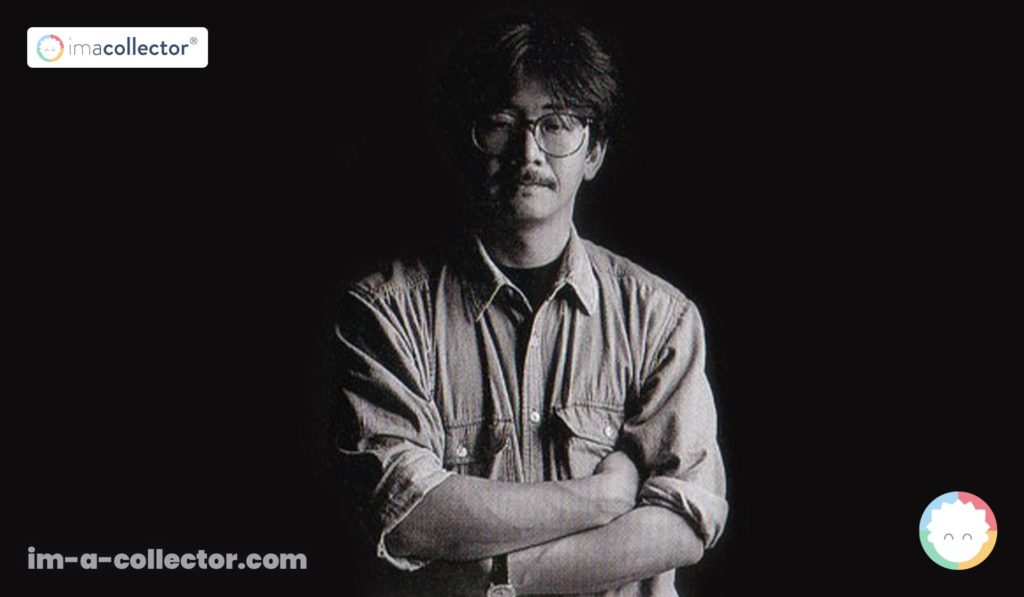 Nobuo Uematsu, jeune, en noir et blanc, sur fond noir, les bras croisés et le regard dirigé vers l’objectif.