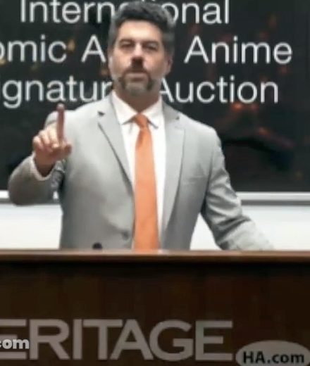 une vente Heritage consacrée aux comics, mangas et anime, avec un commissaire-priseur devant des visuels d’animation japonaise.