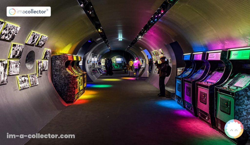 Tunnel d’entrée de l’exposition Video Games & Music, avec bornes d’arcade, éclairages colorés et panneaux documentaires.