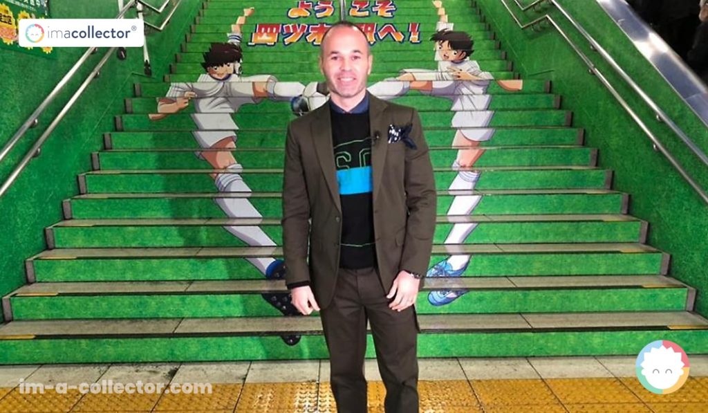 Andrés Iniesta devant un escalier décoré aux couleurs et aux personnages du manga Captain Tsubasa à Tokyo.