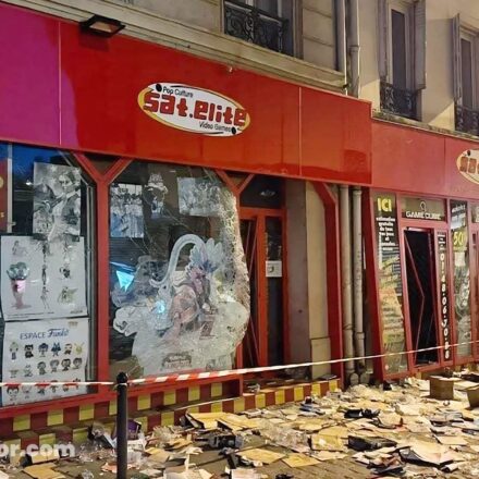 Façade de la boutique Sat.Elite Video Games à Paris, avec ses vitrines brisées et des débris jonchant le trottoir après les pillages.